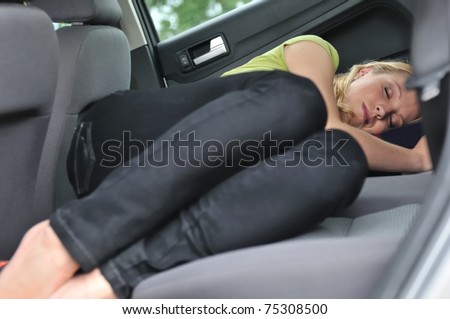 Young beautiful blond woman sleeps in car on back seat - lifestyle portrait