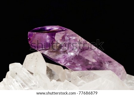 Amethyst sharp shaped crystal energizing on druze of quartz crystals (black background). Amethyst is used in alternative medicine and esoteric for work with energies and is conected with 7th chakra.