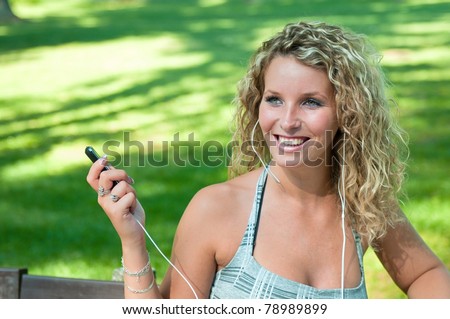 Portrait of young smiling person listening music holding mobile phone