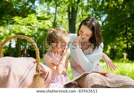 Mother with child are playing while reading book and imitating elephant