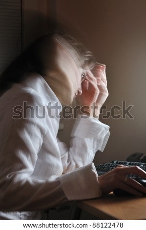 Young unhappy business woman working overtime at computer, night setting, motion blur