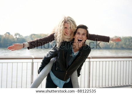 Young couple enjoying life together outdoor - man holding woman who pretends to fly