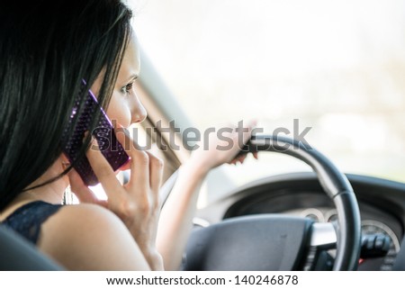 Young woman calling phone while driving car - rear view