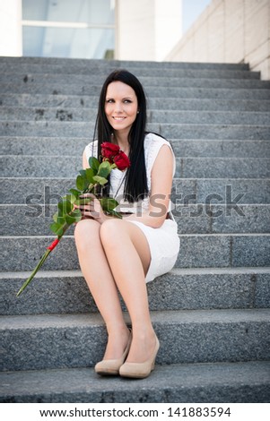 Young beautiful woman with red roses - outdoorfon stairs