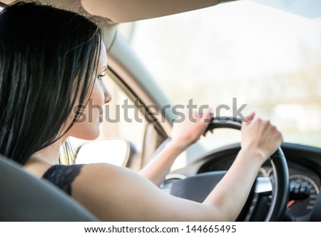 Young beautiful black-haired woman driving car - rear view