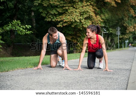 Young sport couple in starting position prepared to compete and run
