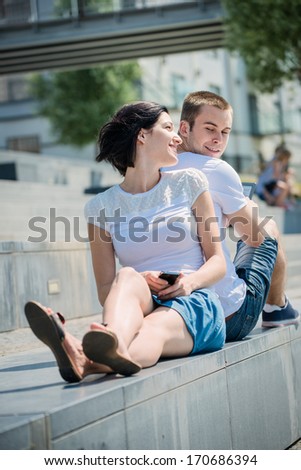 Young couple in street - woman with smartphone, man with tablet