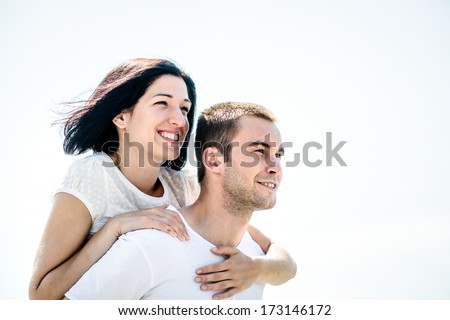 Young couple looking to bright future - happy woman embracing her love around neck
