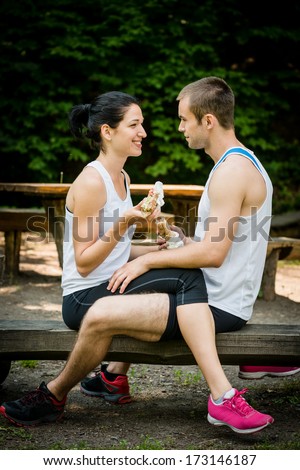 Young couple eating together after jogging outdoor in a forest.