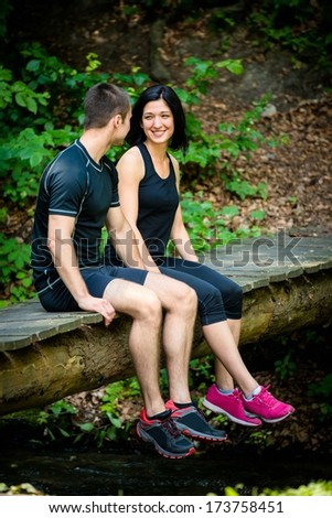 Young sport couple relaxing after sport training on foot bridge in nature