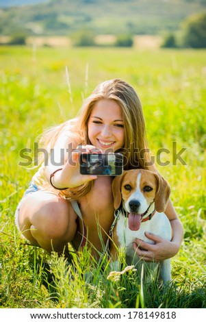 Young woman taking photo of herself and her pet with mobile phone camera