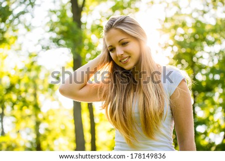 Lifestyle portrait of young happy woman (teen girl) - hand in hair