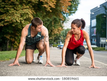 Young sport couple in starting postion prepared to compete, looking on each other