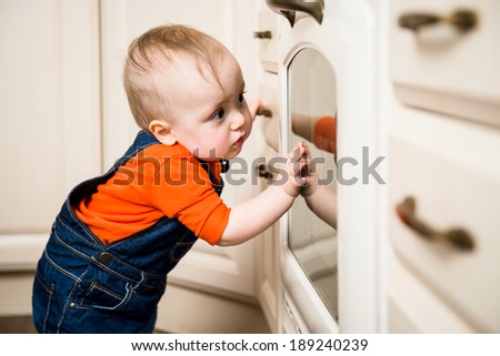 Curious baby watching through glass of kitchen oven