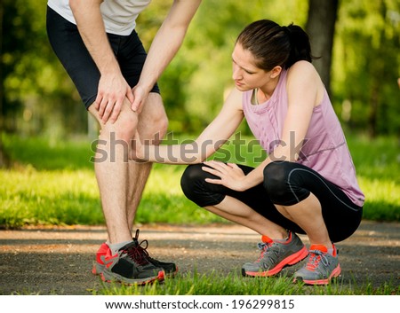 Woman helps to man with injured knee at sport activity
