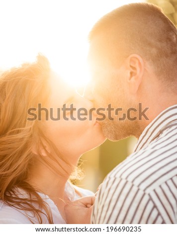Couple kissing at sunset - photographed against sun