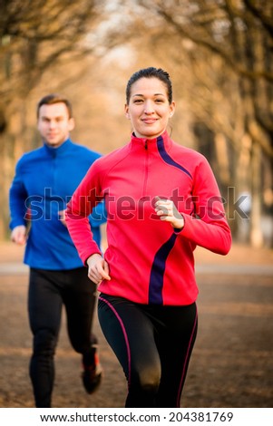 Jogging couple - young man and woman competing, woman first