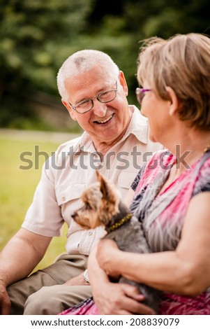 Smiling happy senior couple with their dog pet outdoor in nature