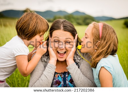 Children blowing whistles to mother\'s ears- outdoor in nature