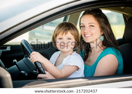 Portrait of mother and child pretend driving car sitting both on front driver seat