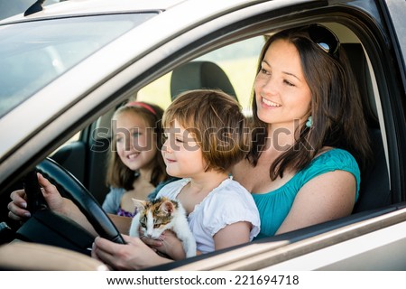 Mother and children pretend driving car sitting all on front seats