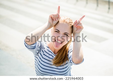 Teenager portrait - smiling girl has fun and pretends she is devil