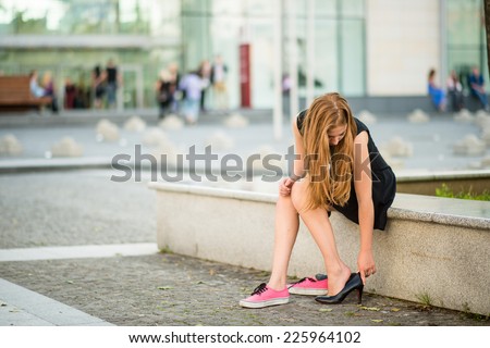 Young woman changes shoes on street high heels instead of sneakers