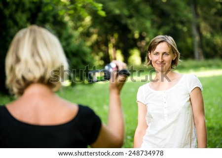 Senior woman is taking video of her adult daughter in nature