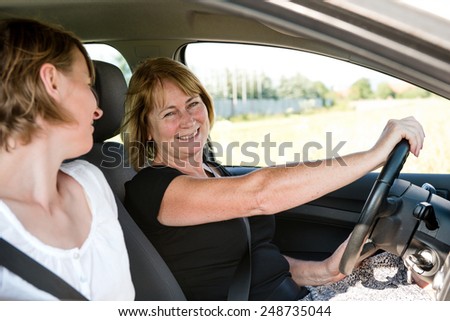 Smiling senior woman driving car with her adult child