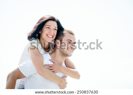 Young couple looking to bright future - happy woman embracing her love around neck
