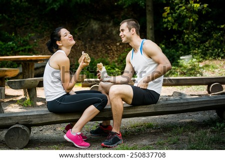 Young couple having fun while eating after sport training outdoor in nature
