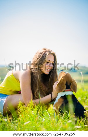 Lifestyle photo of happy young girl with her pet (beagle dog) - outdoor in nature