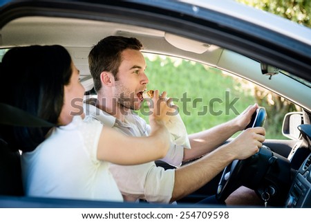 Couple in car - man is driving and woman is feeding him