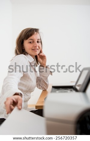 Business person reaching hand and taking paper from printer on workplace - detail
