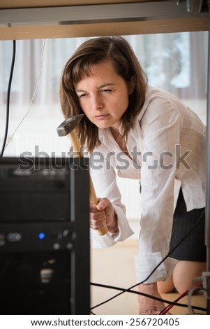Young business woman having problem with computer and trying to recover it with hammer