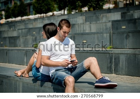 Young couple in street - man with smartphone, woman with tablet