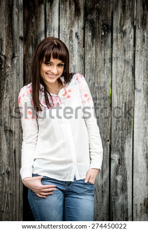 Portrait of beautiful smiling woman in front of faded wooden fence