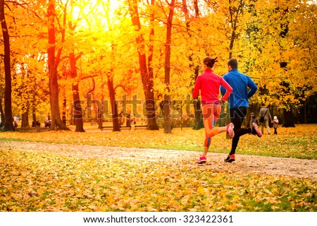 Young couple running together in park - fall nature