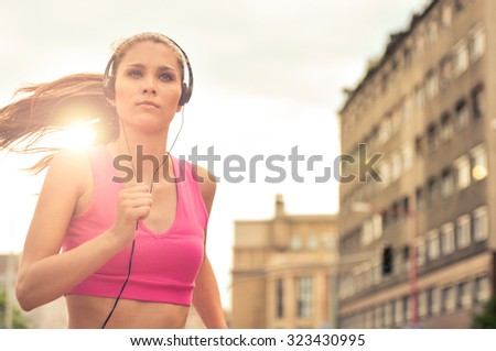 Person (young beautiful woman) listening music running (jogging) in city street