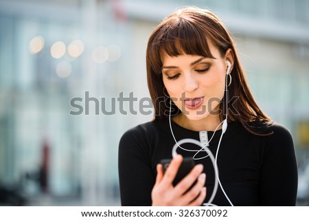 Young woman sticking out tongue while making video call in street