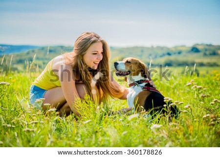 Lifestyle photo of happy young girl with her pet (beagle dog) - outdoor in nature