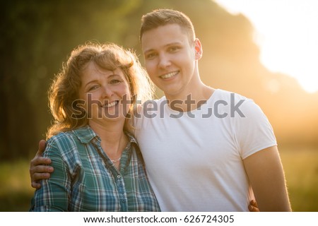 Mature woman with her adult son. Side hug. Family bond concept.