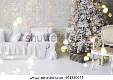 Holiday decorated room with Christmas tree and armchair with blanket. White interior with lights.