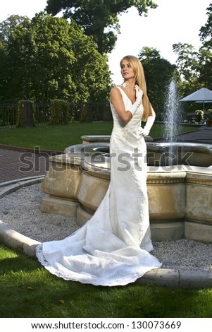Beautiful, elegant bride standing by the fountain in italian manor