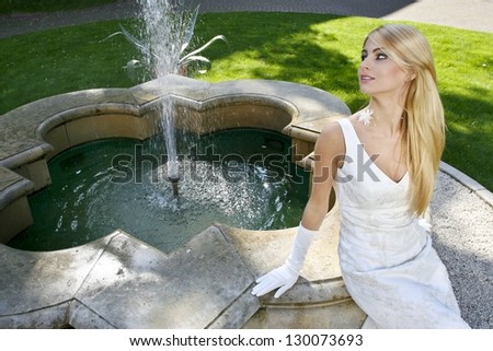Beautiful, elegant bride relax at the fountain in italian manor