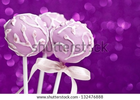 Cake pops on purple background. Sweets decorated with icing.