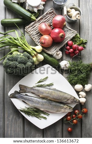 Top View On Huge Wooden Table: Two Raw, Fresh Rainbow Trouts Among Vegetables. Idea Of Healthy Living And Valuable, Natural Food.