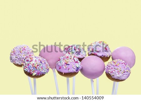 Pink cake pops on yellow background. Copy space