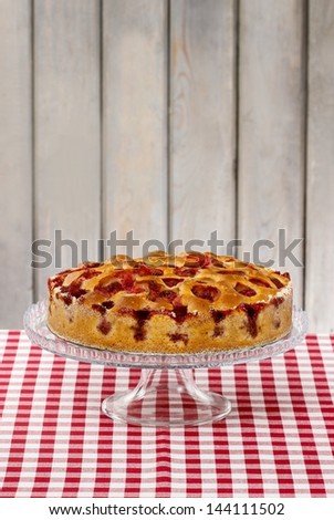 Strawberry pie on cake stand, wooden background