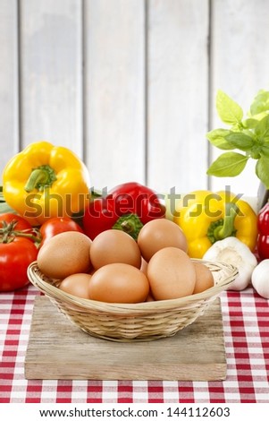 Stack of eggs, fresh vegetables in the background
